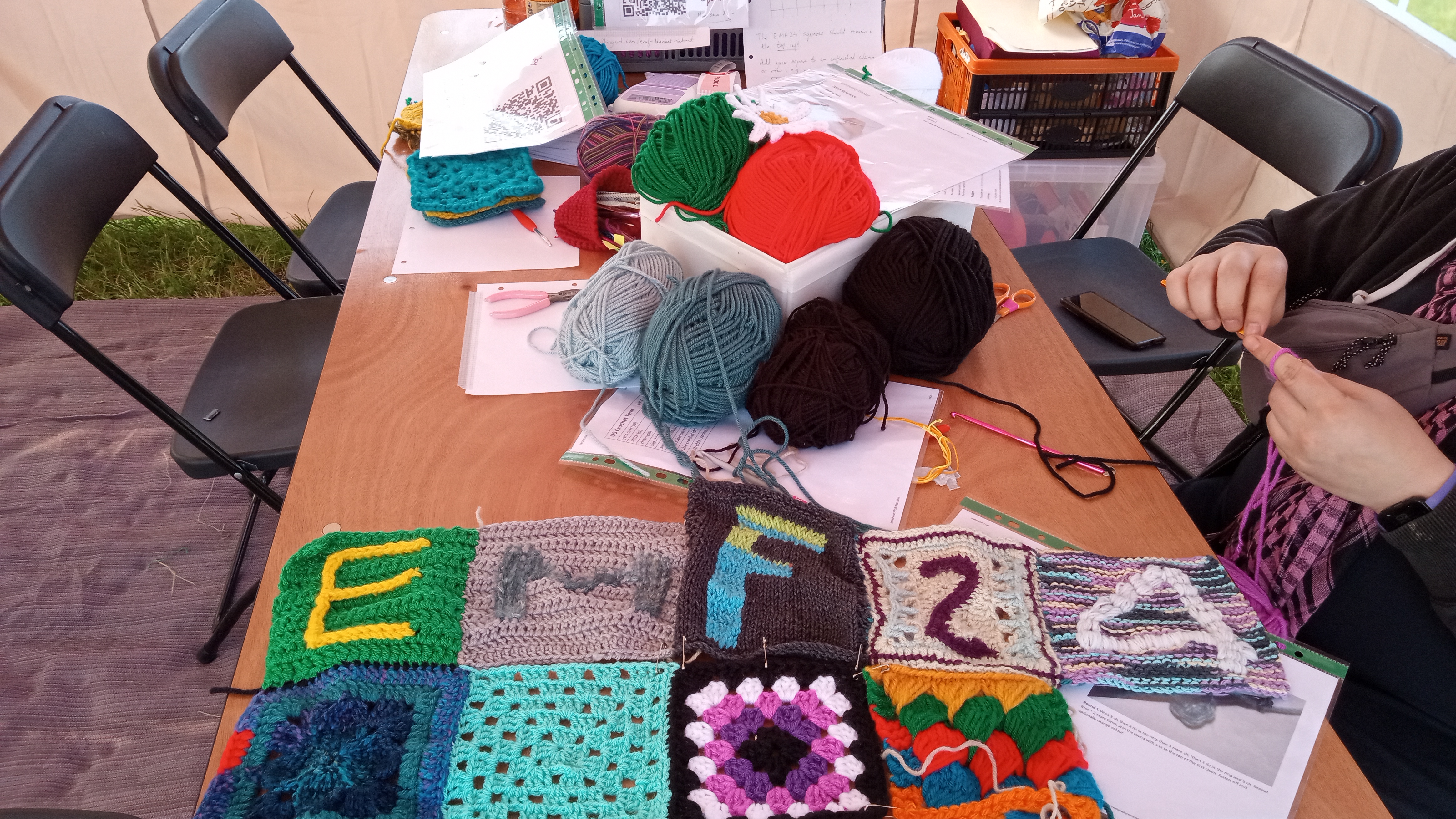 Blanket maker table with assorted yarn and a few finished squares